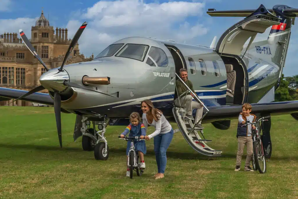 Family playing infront of Pilatus PC-12 on grass runway